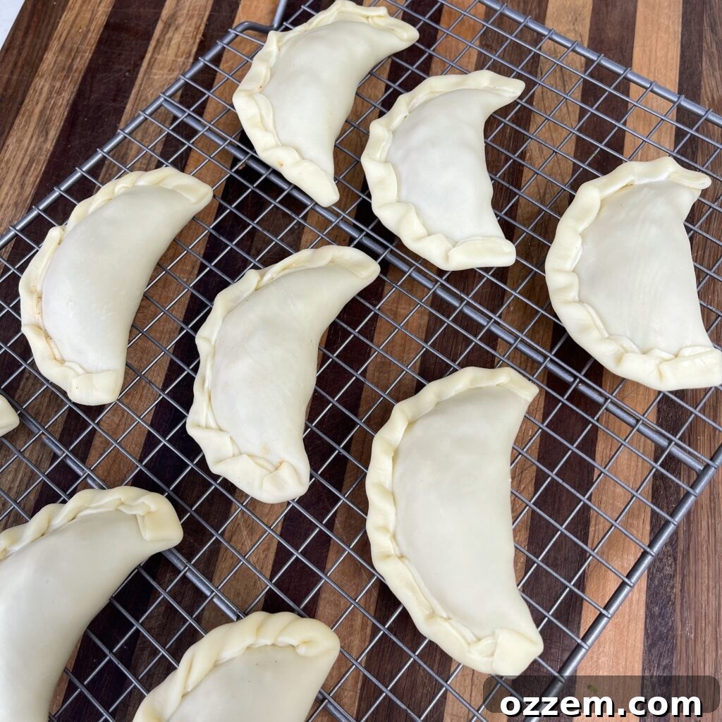 Crimping the edges of the empanada to seal it securely.