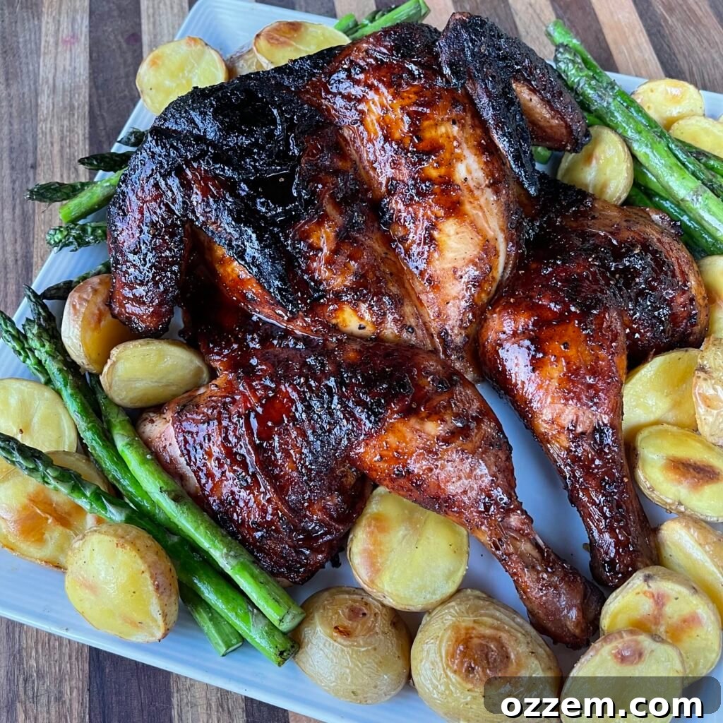 Perfectly grilled BBQ spatchcock chicken, golden brown and juicy, served with roasted potatoes and asparagus.