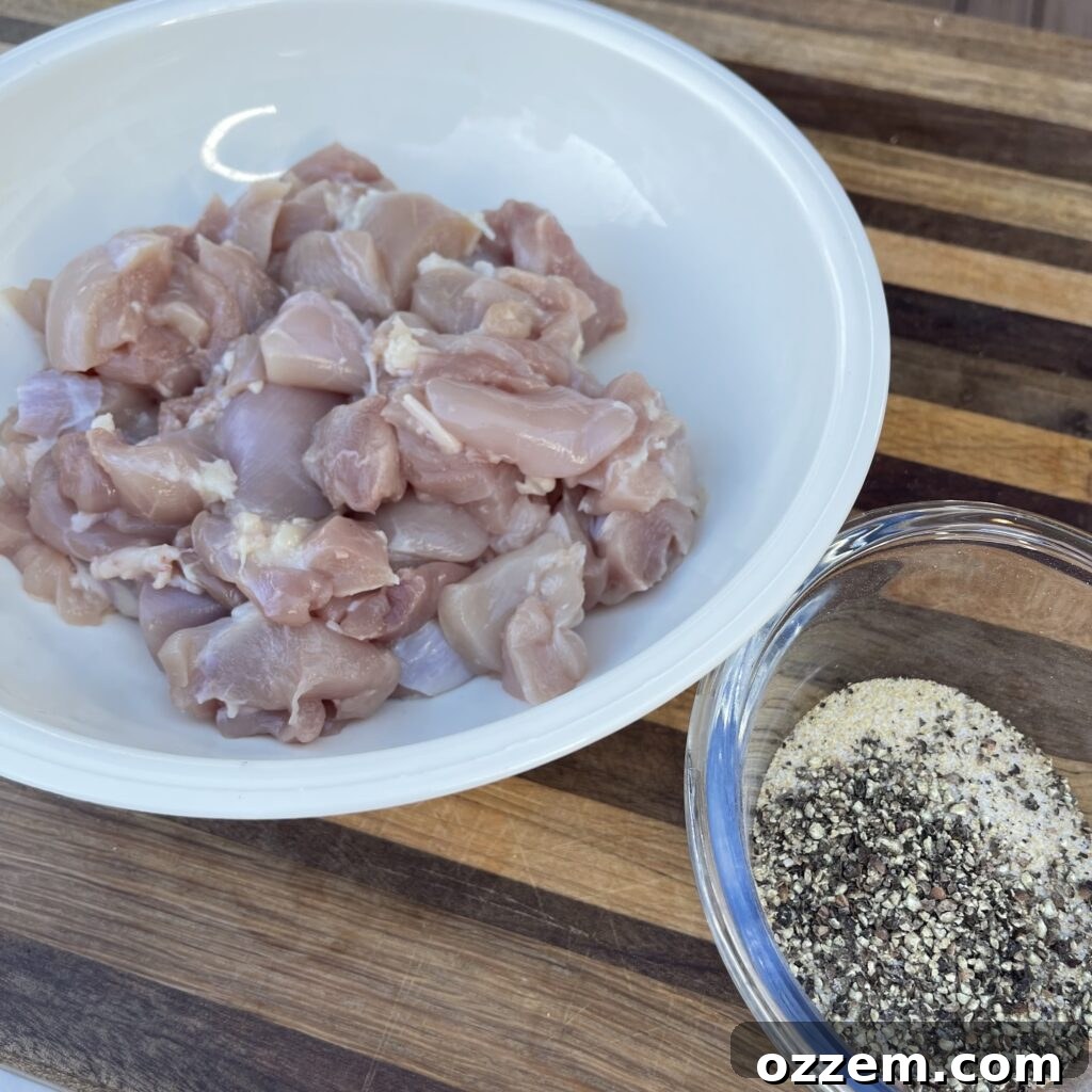 Raw chicken thighs sliced into uniform bite-sized pieces in a mixing bowl, ready for seasoning.