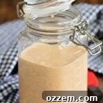 White BBQ sauce in a jar with the lid partially closed.