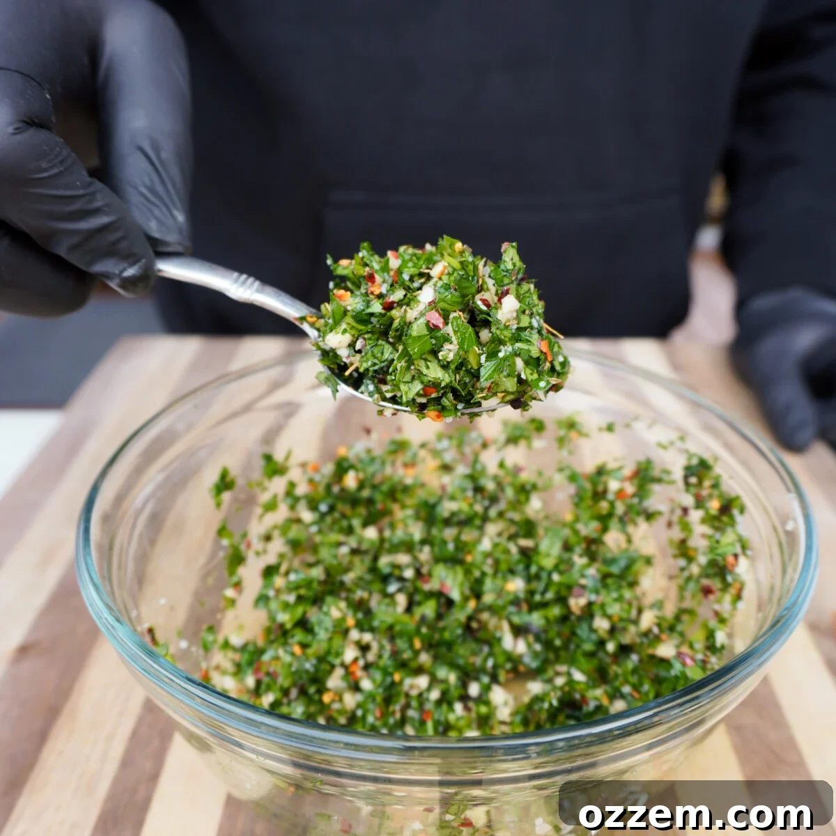 All chopped chimichurri ingredients, including herbs, garlic, and spices, in a bowl.
