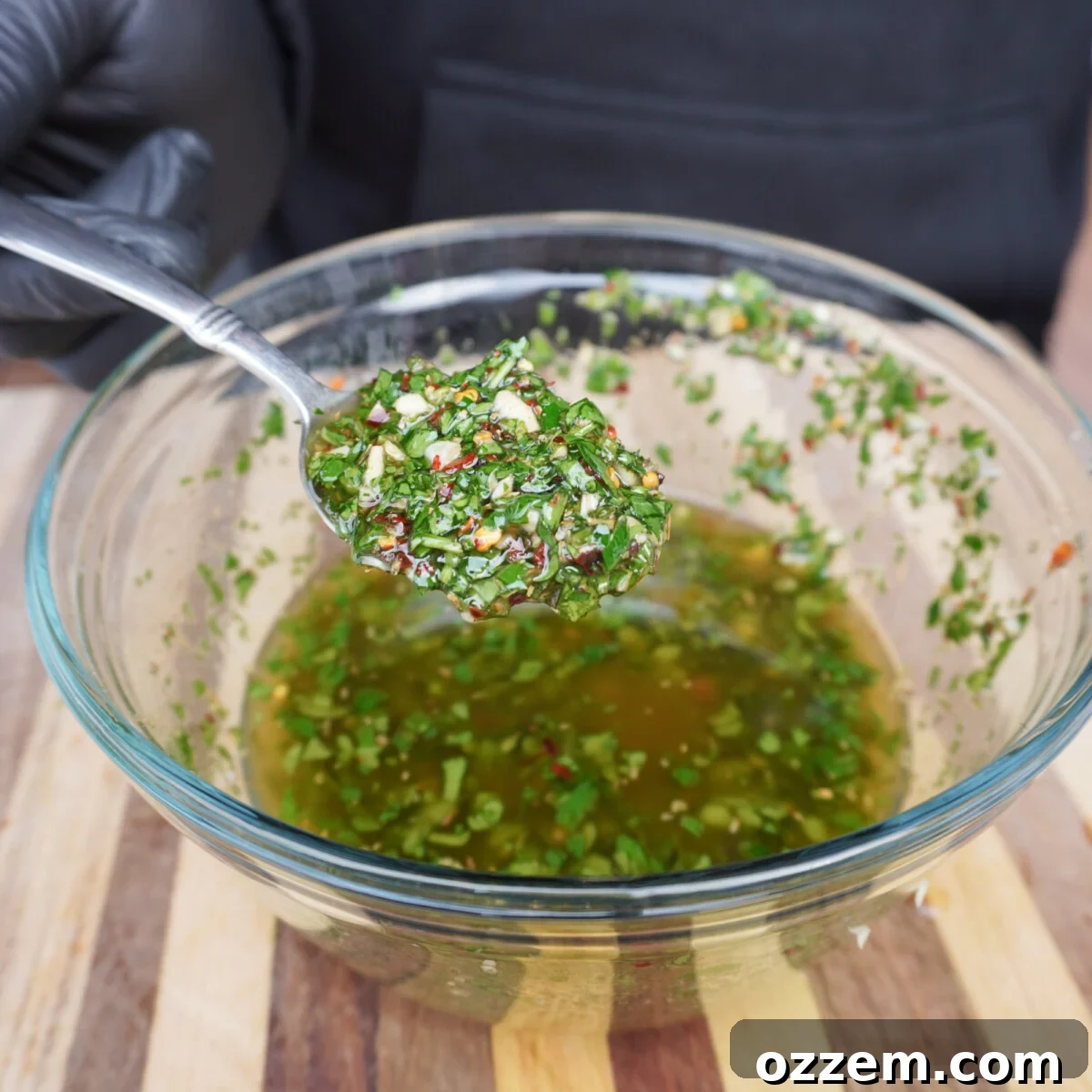 Finely chopped herbs, garlic, and spices soaking in olive oil and red wine vinegar.
