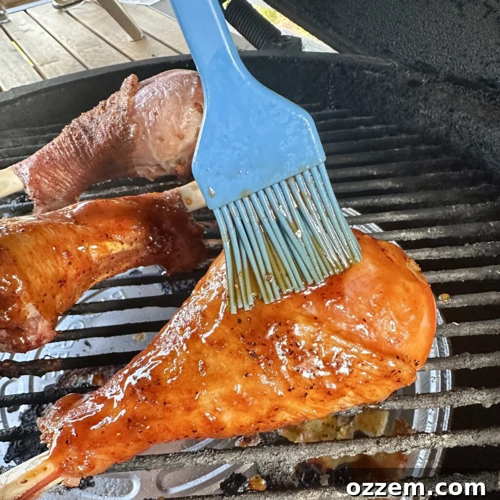 Large BBQ turkey legs cooking on a gas grill, surrounded by smoke.