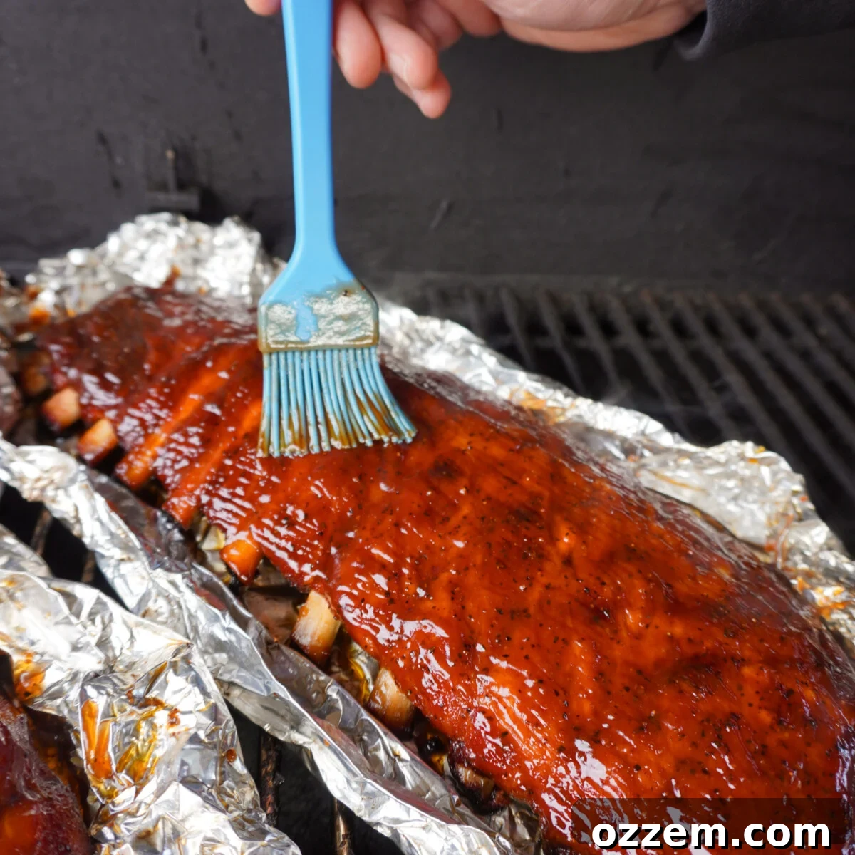 Succulent Slow-Smoked Baby Back Ribs 12 Brushing BBQ sauce onto classic baby back ribs on the smoker.