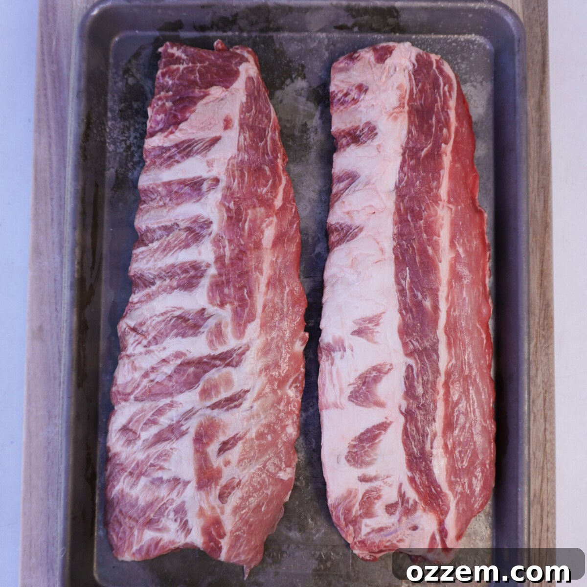Succulent Slow-Smoked Baby Back Ribs 3 Raw baby back ribs on a sheet pan, ready for prep.