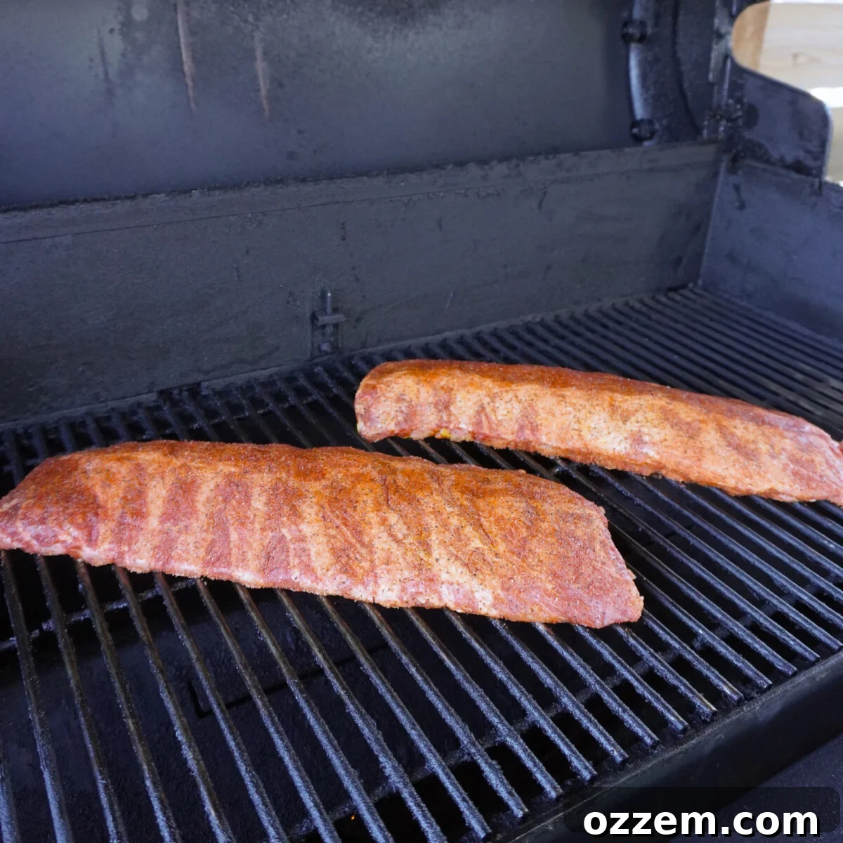 Succulent Slow-Smoked Baby Back Ribs 8 Baby back ribs smoking directly on the grates of a pellet grill, meat side up.