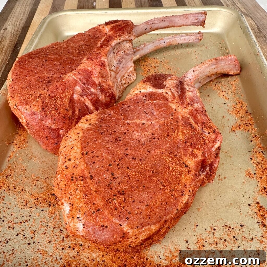 The Ultimate Juicy Pork Chops 4 Generously seasoned thick-cut pork chops resting before grilling.