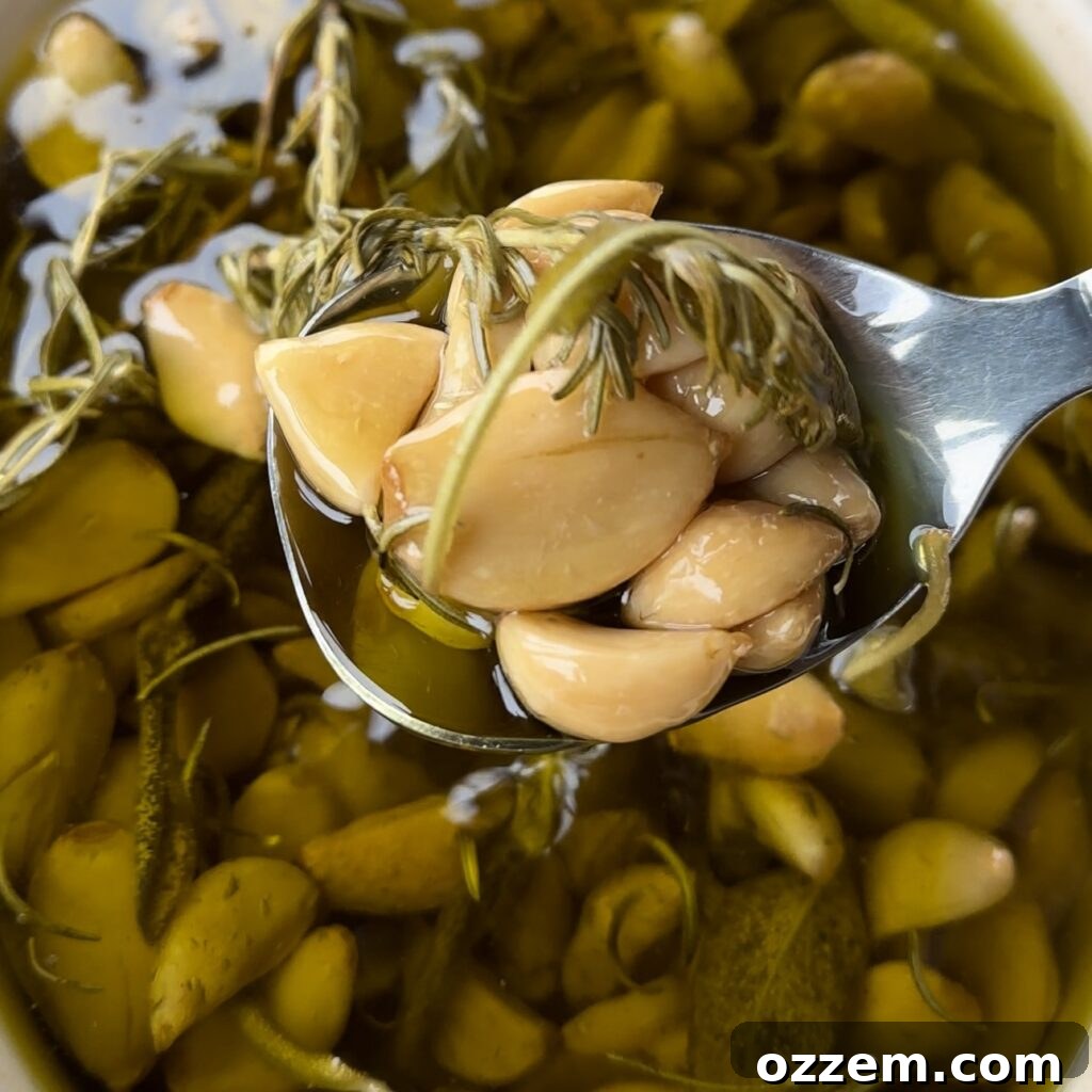 Jars of homemade garlic confit with herbs, ready for storage.