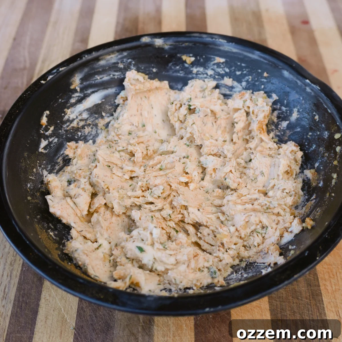 Glass bowl containing a vibrant mixture of herb compound butter, ready to be applied.