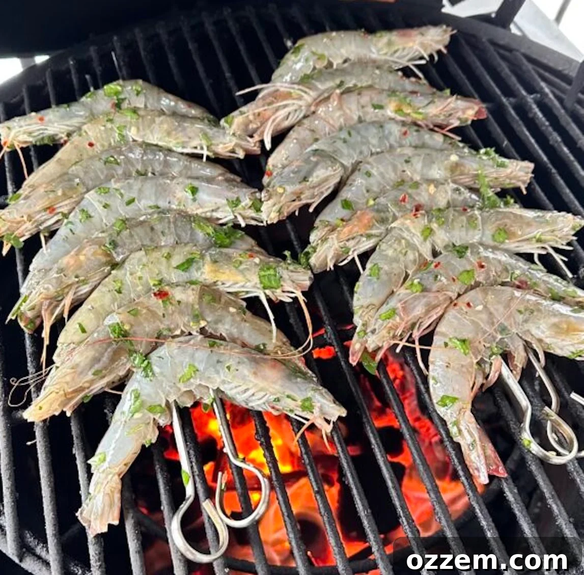 Grilling whole shrimp skewers over direct heat on a barbecue grill, smoke rising.