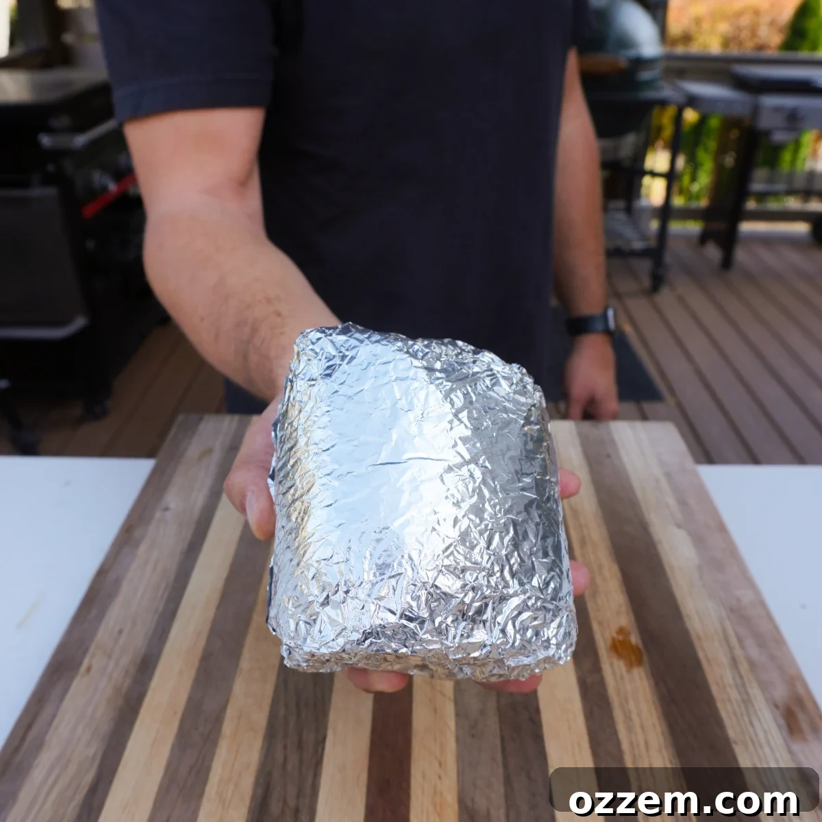 Smoked beef roast tightly wrapped in aluminum foil, resting after being removed from the grill.