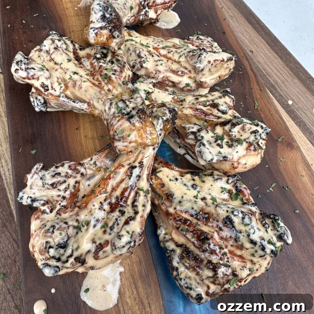Grilled butterflied chicken drumsticks coated in Alabama white sauce