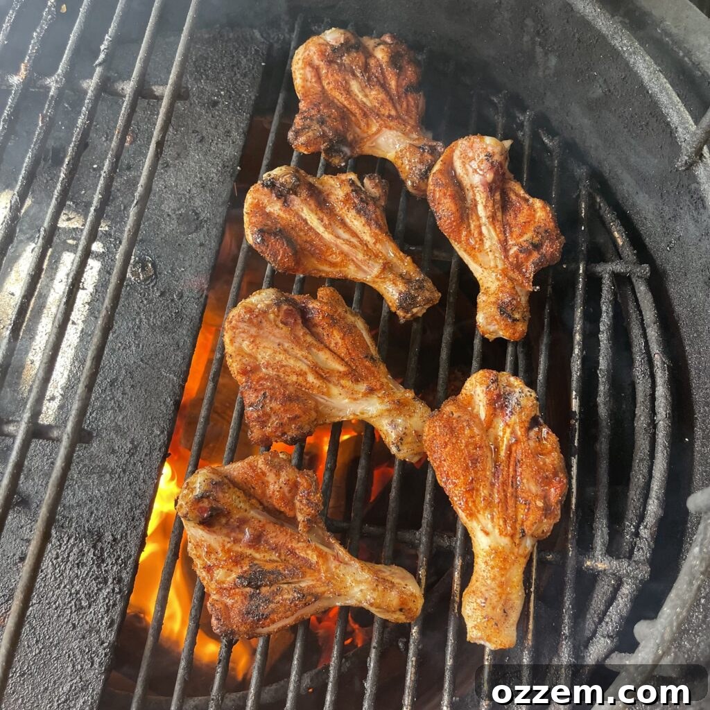 Butterflied chicken drumsticks grilling on direct heat
