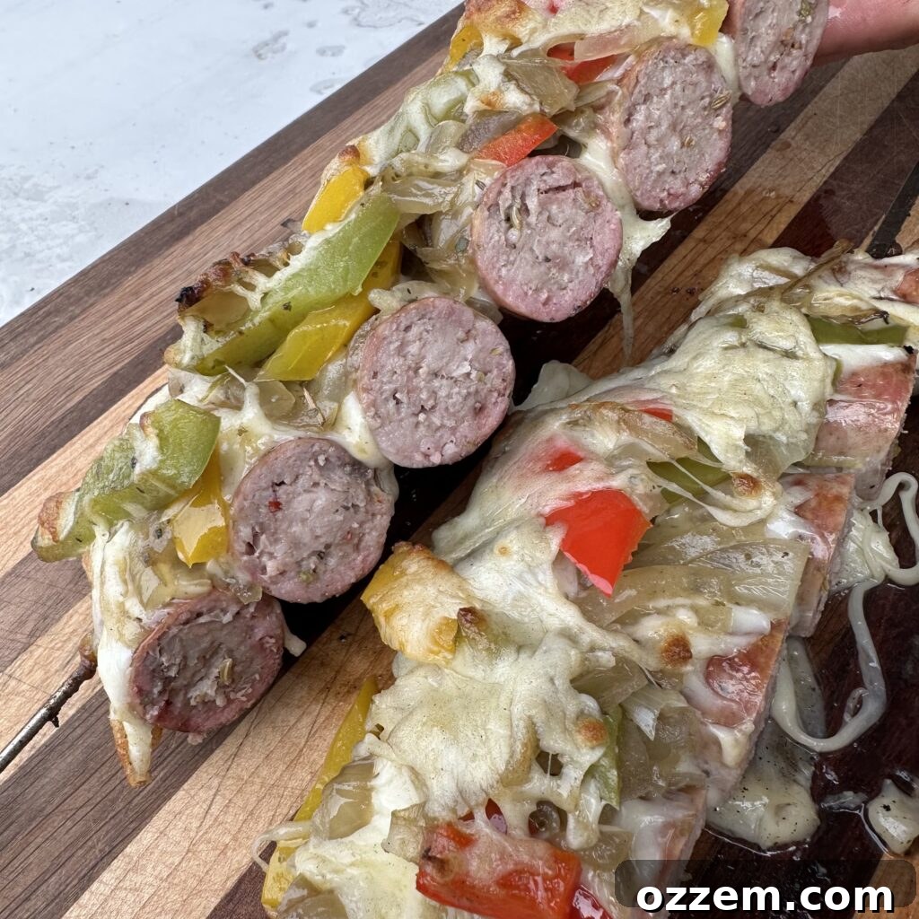 Two beautifully charred loaded Italian sausage skewers, topped with melted cheese and sautéed peppers, resting on a grill grates.