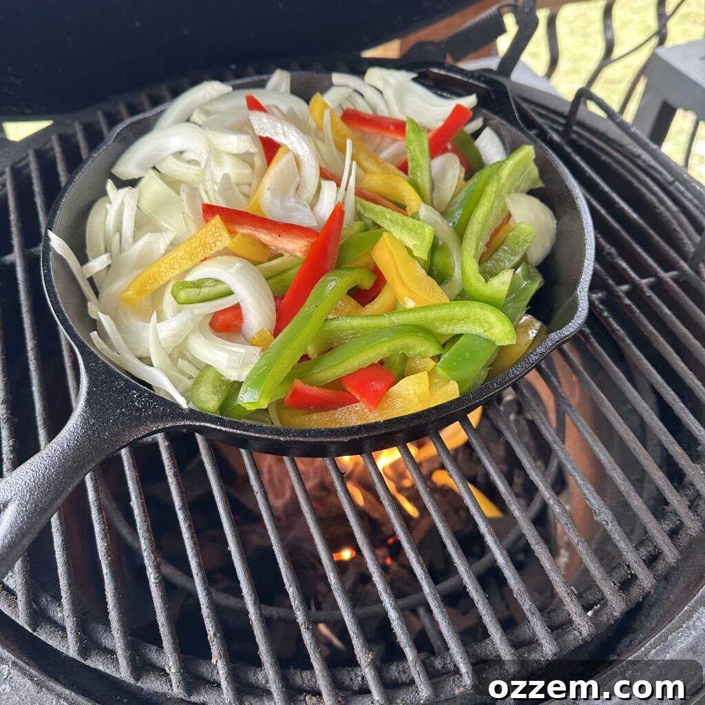 Freshly sliced bell peppers and onions in a cast iron pan, seasoned and ready for the grill, showcasing vibrant colors.