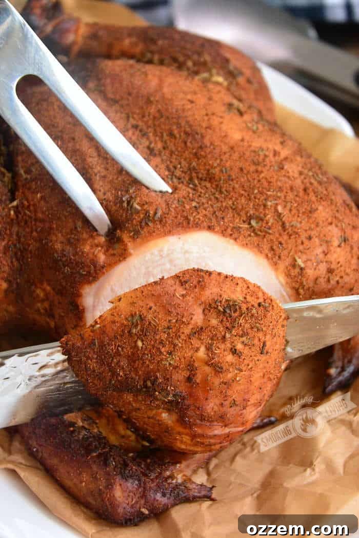 slicing into the smoked chicken breast with a knife and holding with a fork