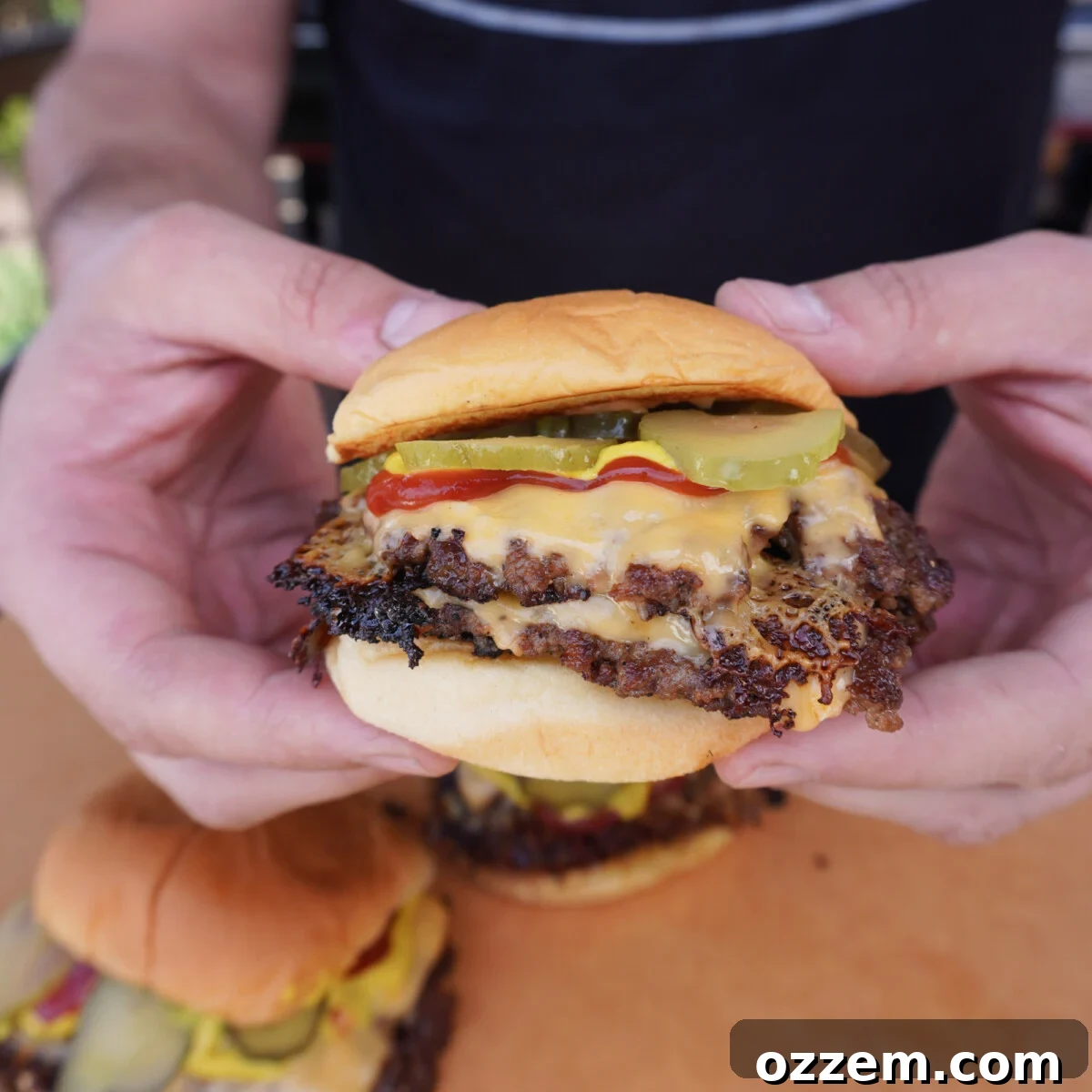 A fully assembled smash burger with pickles, onions, cheese, and two patties.