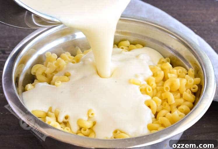 Smoky Mac and Cheese Delight 4 Close-up shot of a rich, golden cheese sauce being poured into a bowl of cooked elbow macaroni, ready for mixing.