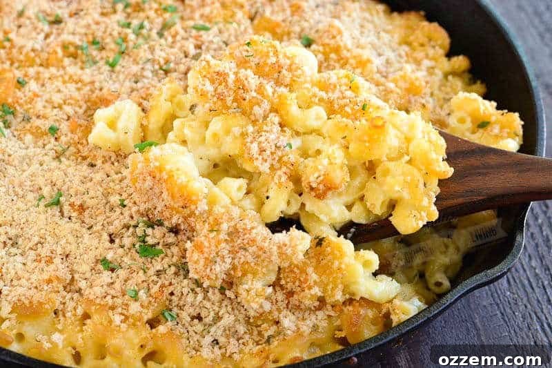 Smoky Mac and Cheese Delight 7 A large serving spoonful of golden, bubbly smoked mac and cheese being lifted from a cast iron skillet, showing its rich texture.