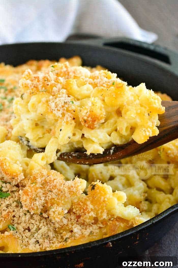 Smoky Mac and Cheese Delight 8 A close-up shot of a spoon pulling out a serving of hot, cheesy smoked mac and cheese from a cast iron skillet.