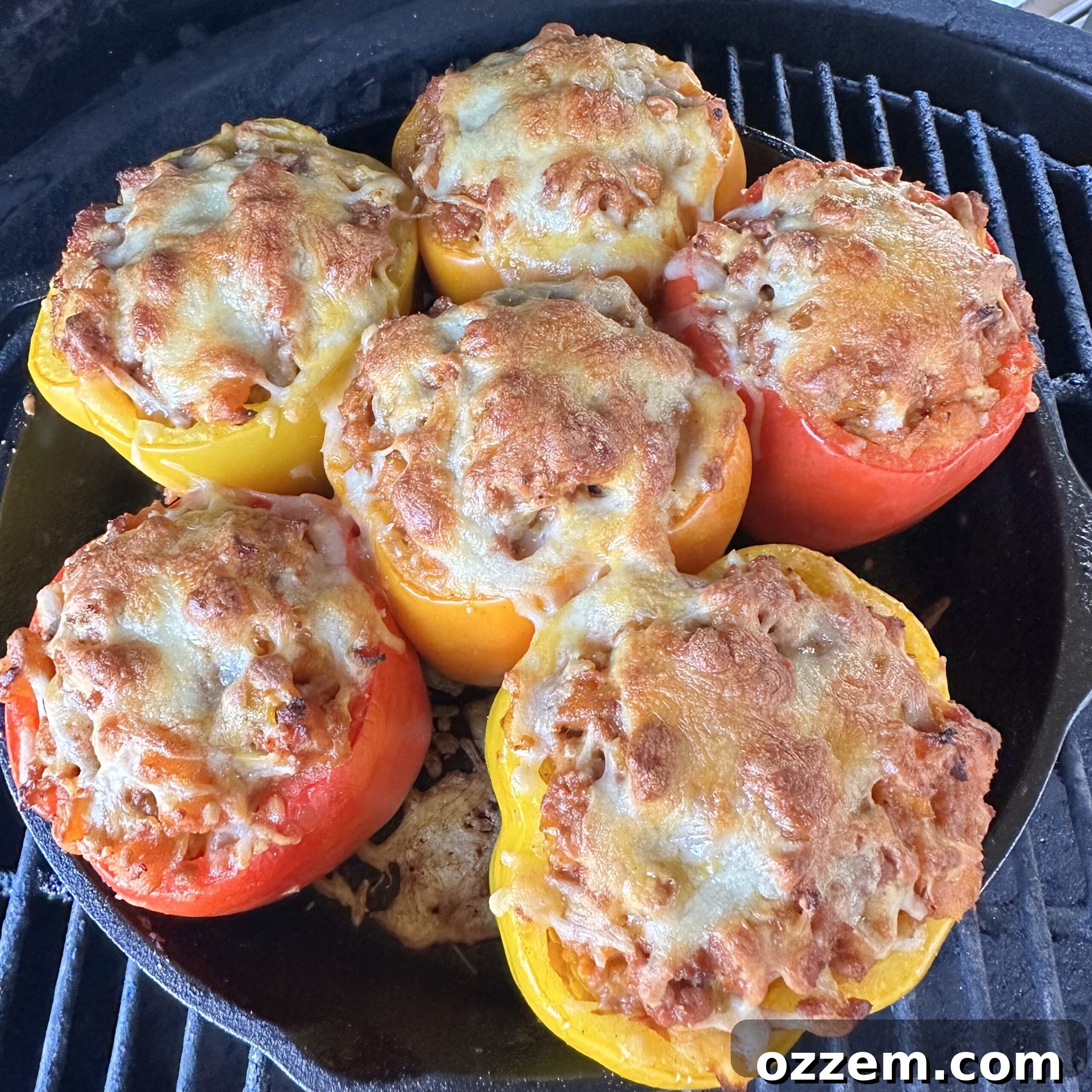 Stuffed bell peppers cooking on the grill in a cast iron skillet.