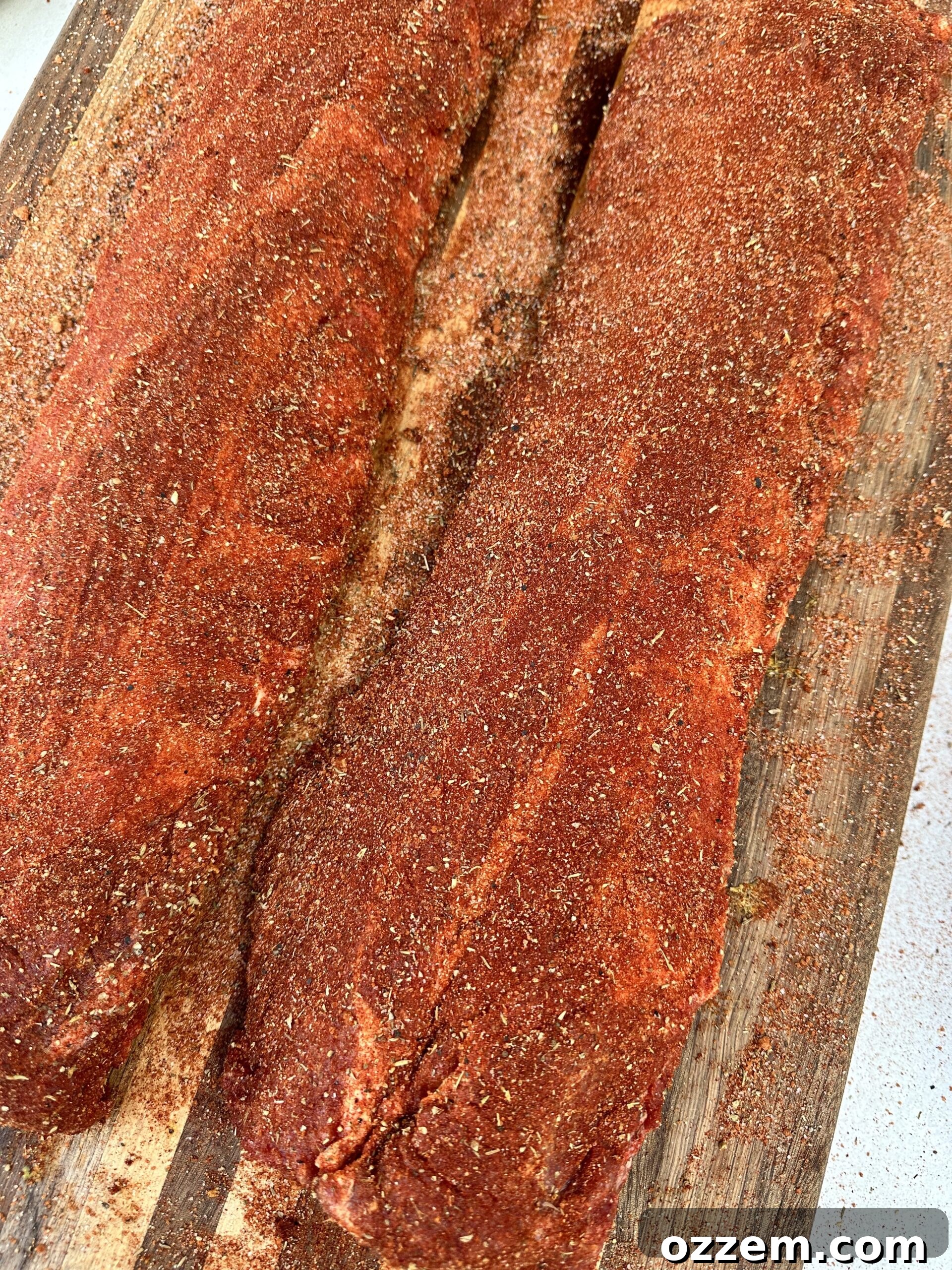Two racks of baby back ribs generously seasoned with Memphis dry rub, ready for the smoker.