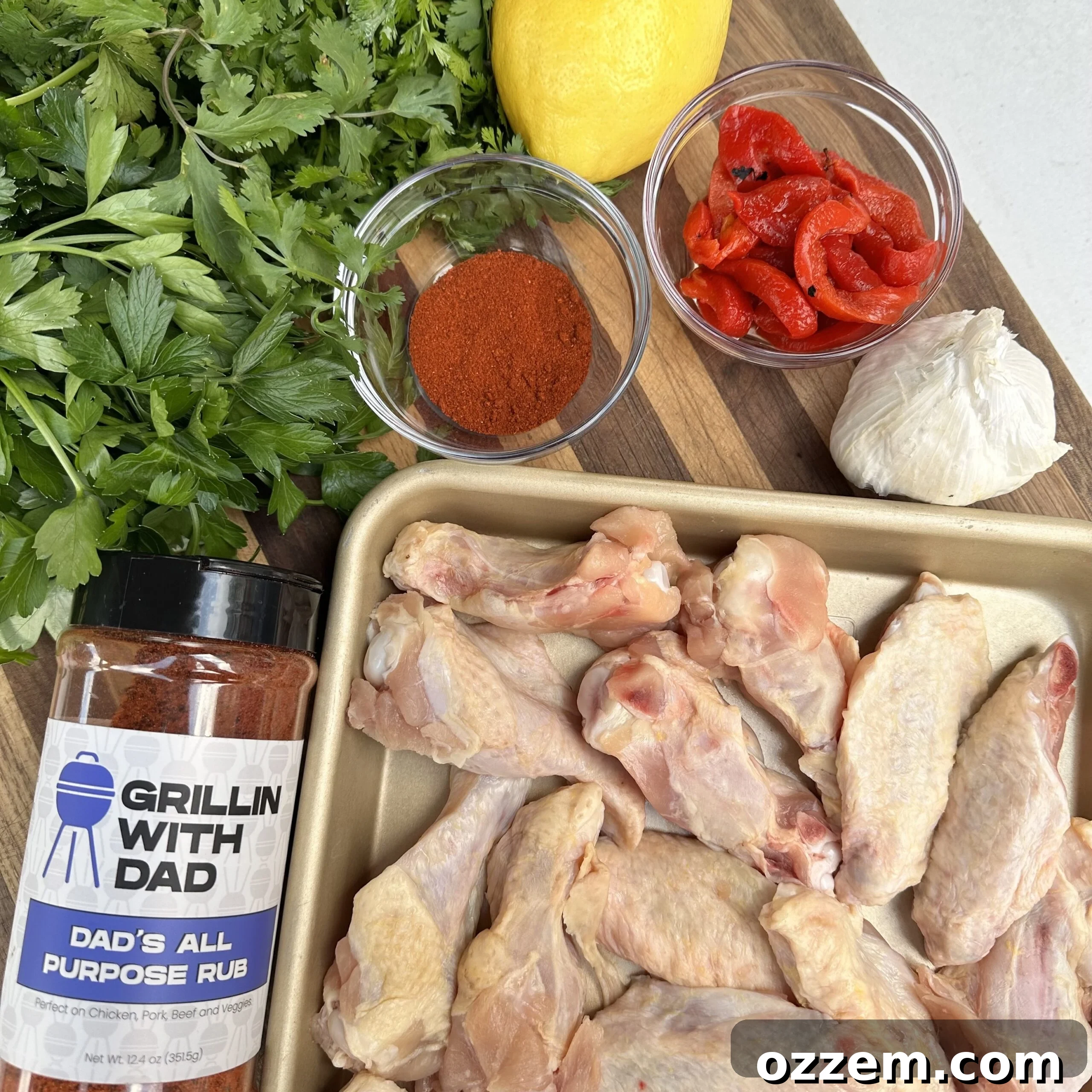 Ingredients for wings in red chimichurri sauce, including herbs, lemon, peppers, and chicken.