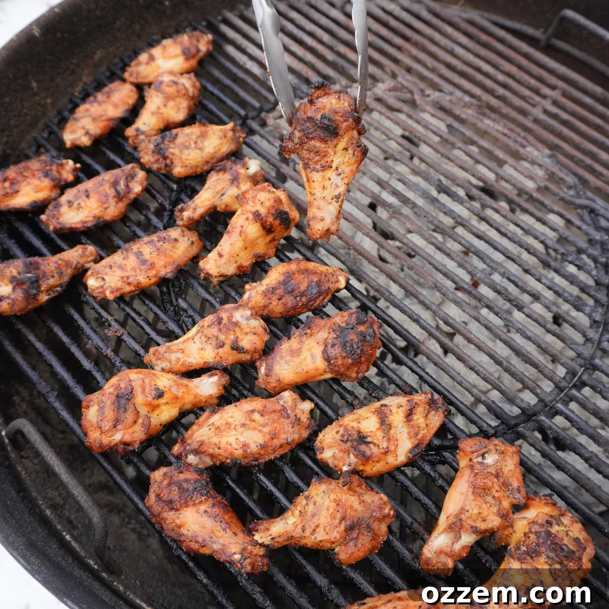 Moving grilled chicken wings from indirect to direct heat for a final crispy char.