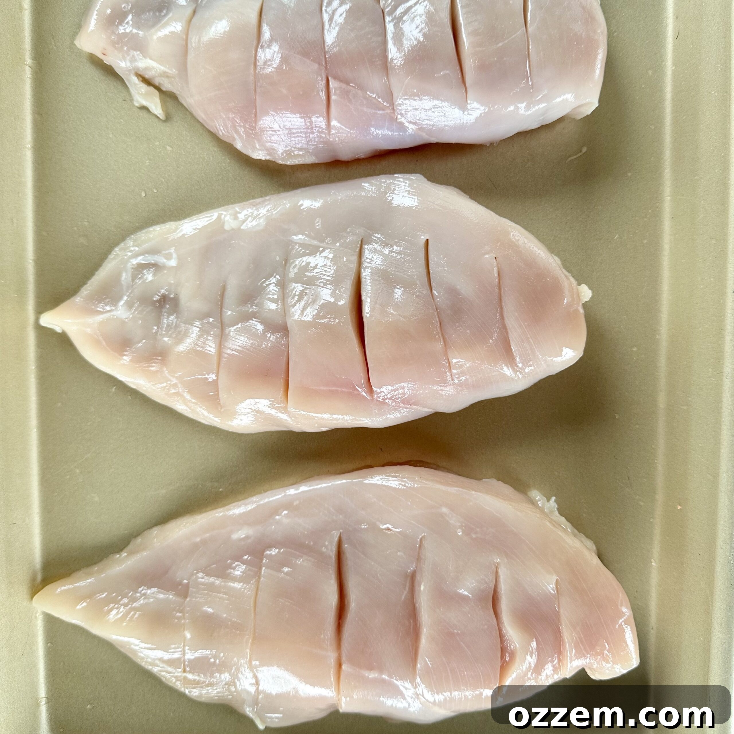 Chicken breast with hasselback slits cut, ready for stuffing.
