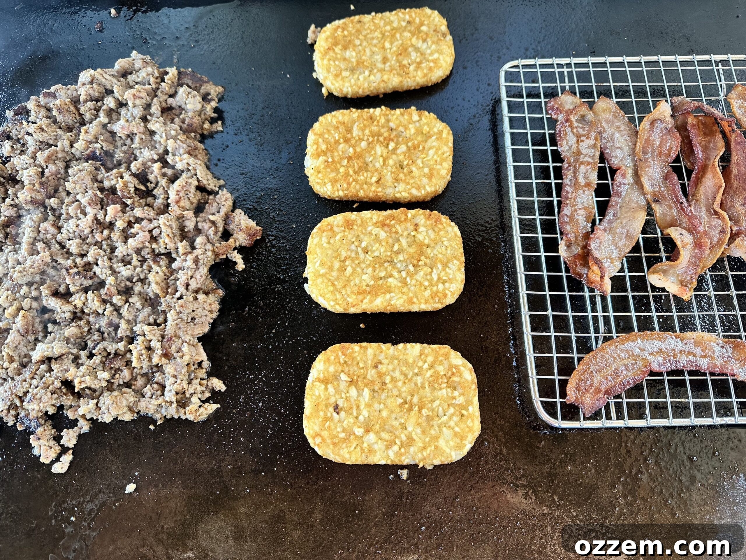 Various breakfast crunchwrap ingredients, including bacon, hash browns, sausage, and eggs, cooking on a griddle.