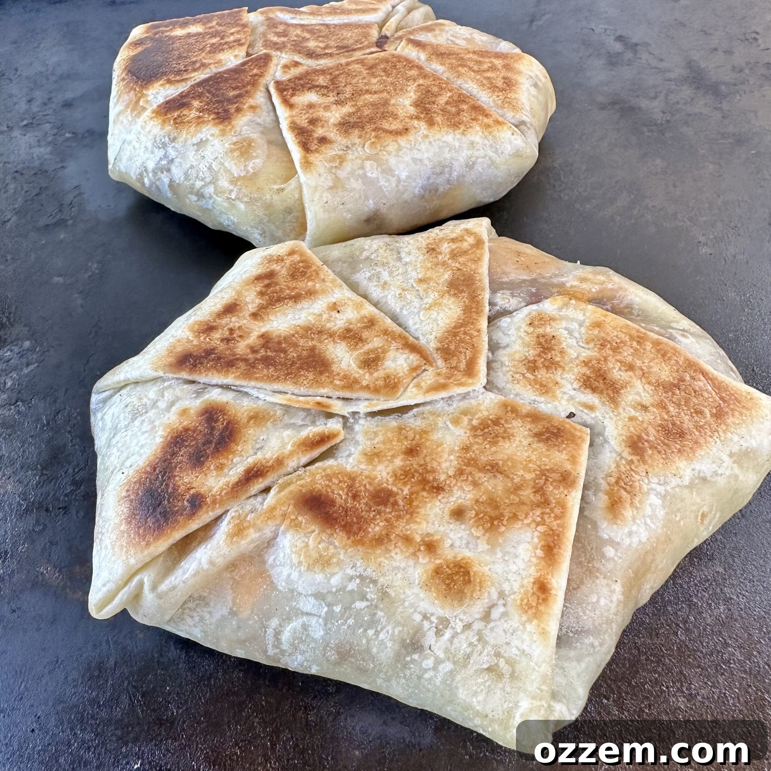 Breakfast crunchwrap wrapped and sealed, cooking seam-down on the griddle for crisping.