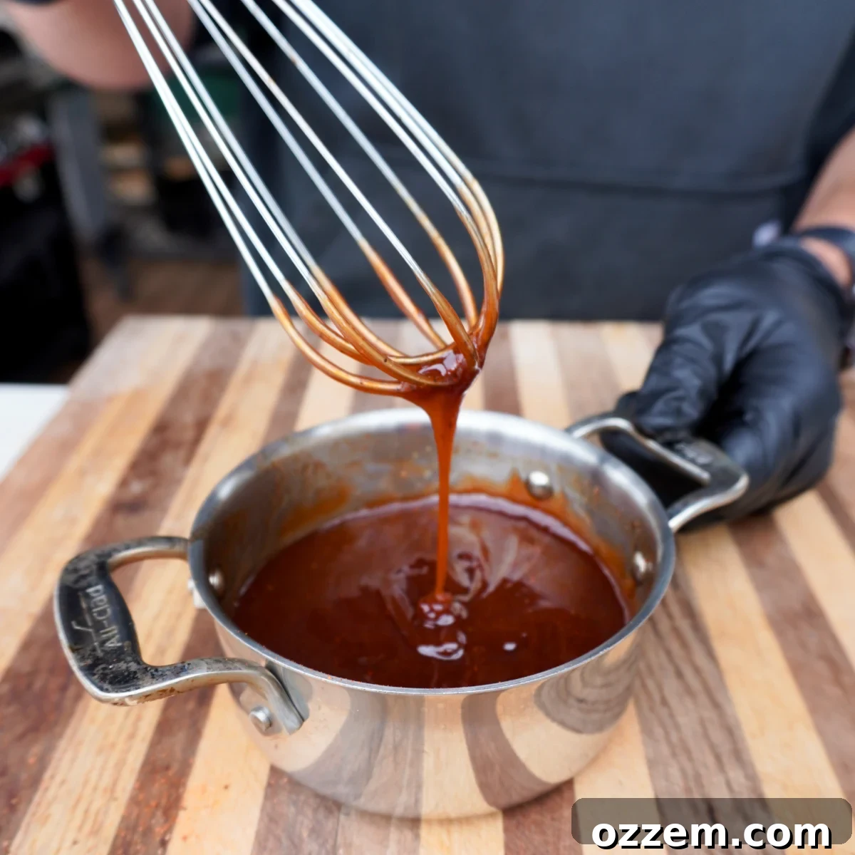 Rich homemade BBQ sauce simmering gently in a saucepan.