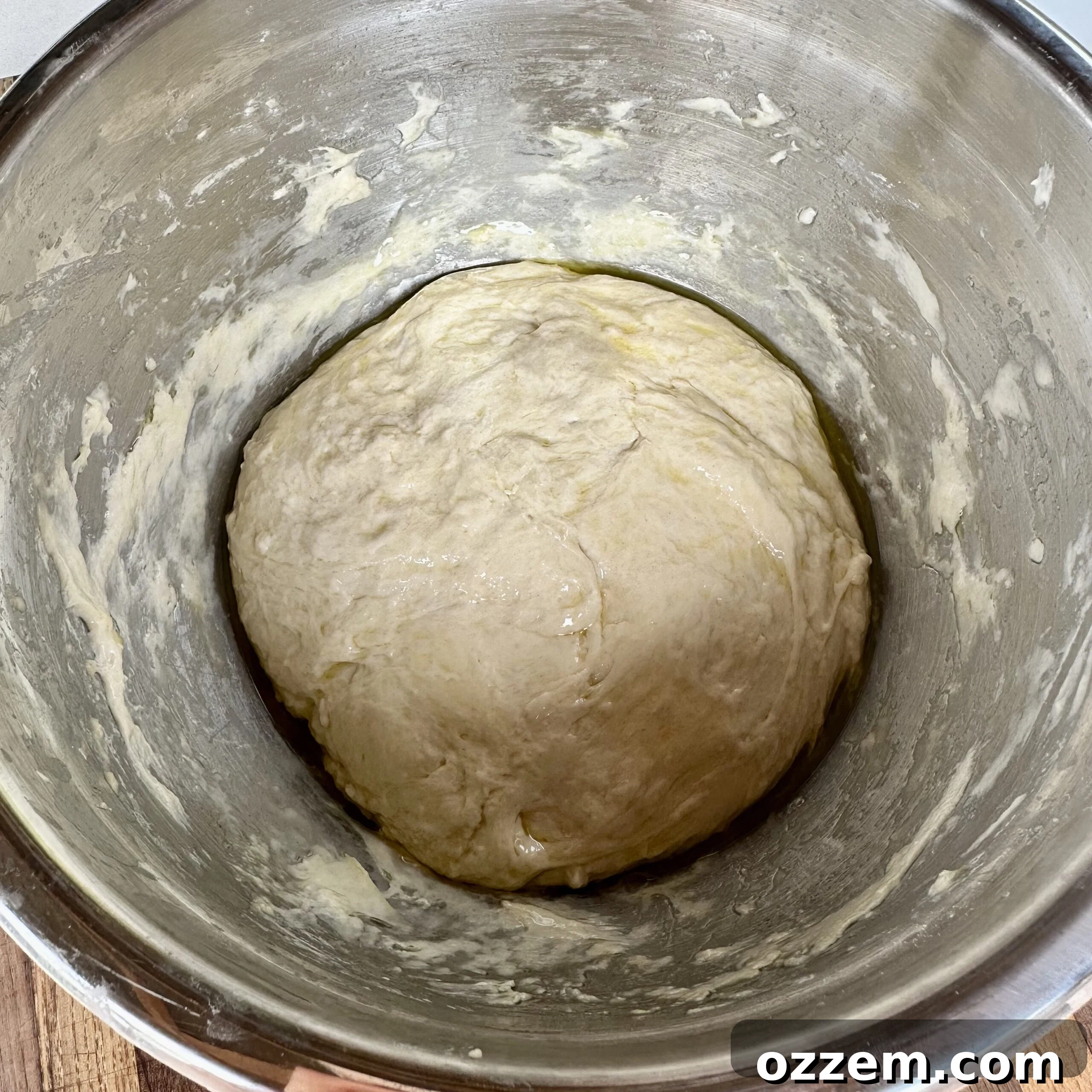 Sticky, freshly mixed focaccia dough in a large mixing bowl, covered with a kitchen cloth.