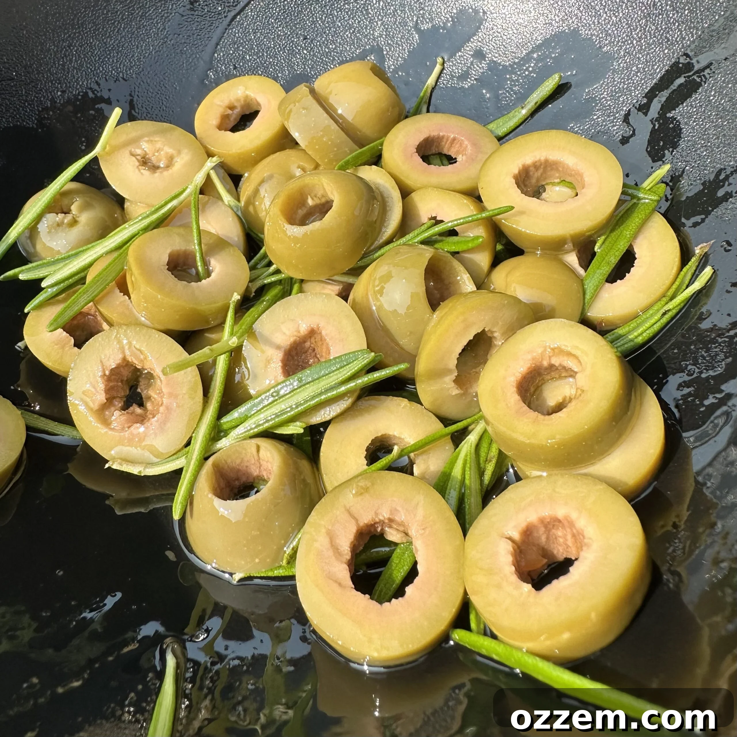 Fresh rosemary sprigs and sliced green olives, ready to top focaccia dough.