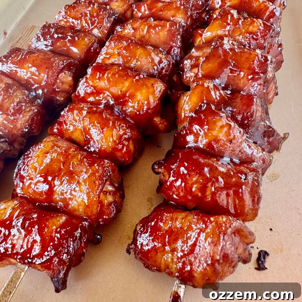 Perfectly grilled bacon wrapped chicken skewers glistening with BBQ sauce.
