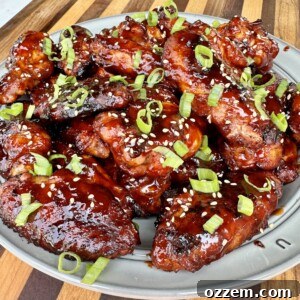Close-up of grilled gochujang wings, garnished with sesame seeds and green onions.