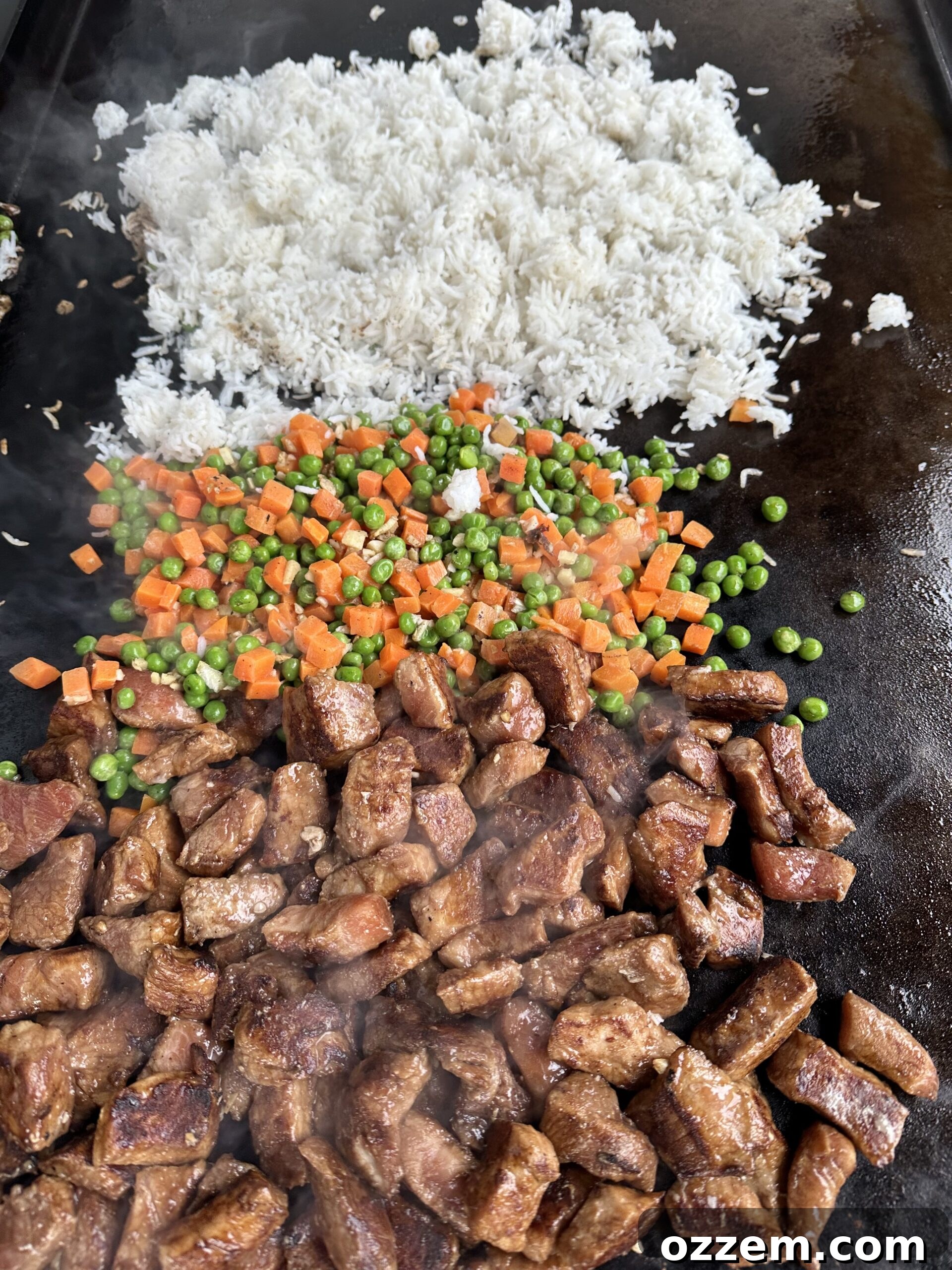 Pork cooking on a griddle alongside vegetables