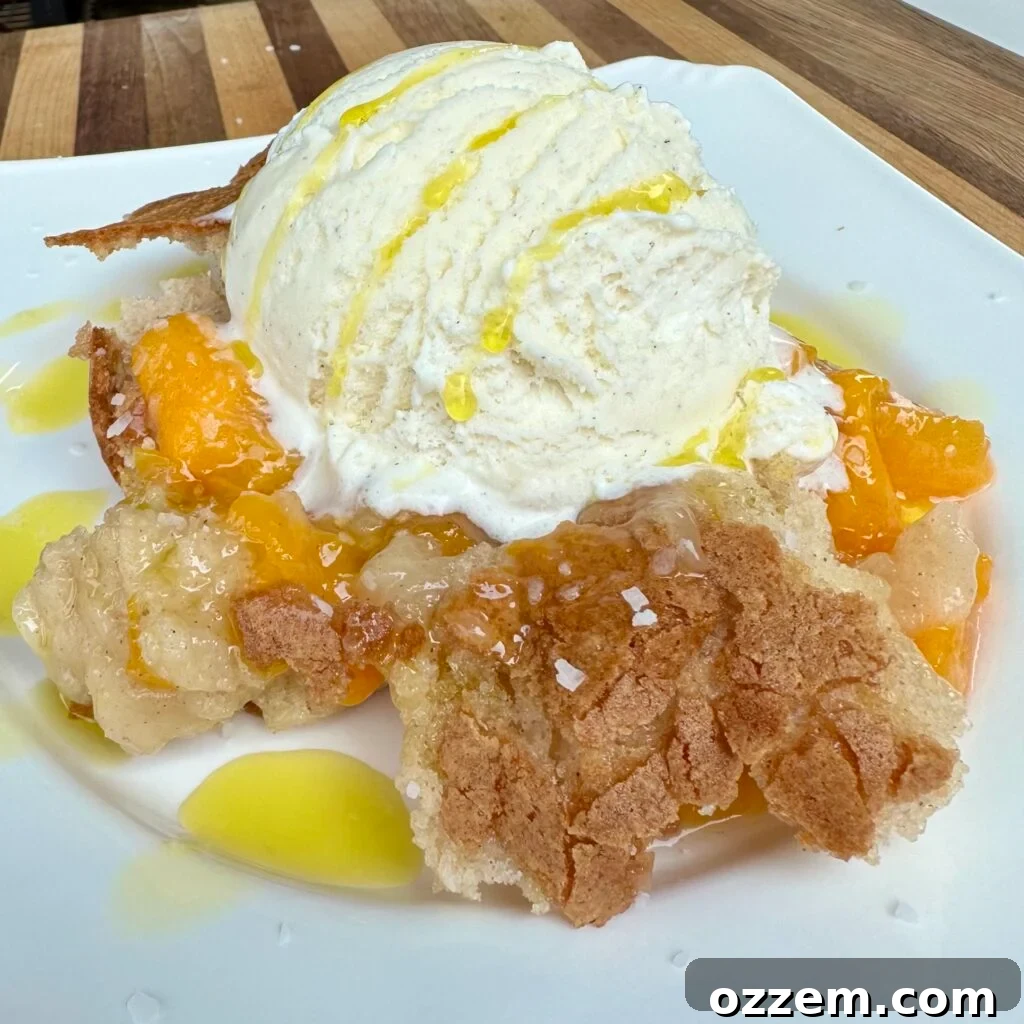 A delicious grilled peach cobbler topped with a scoop of vanilla ice cream, ready to be served from a baking dish.