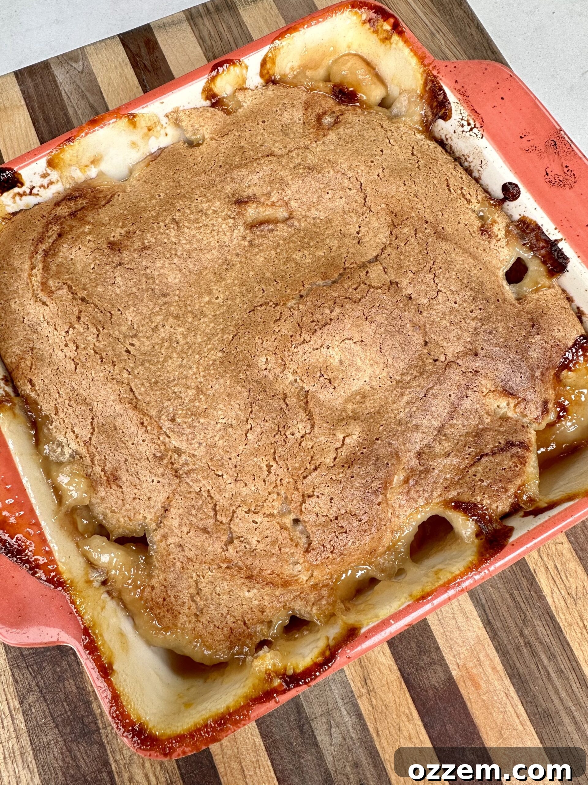 A freshly grilled peach cobbler served in a bowl with a scoop of melting vanilla ice cream and a drizzle of olive oil.