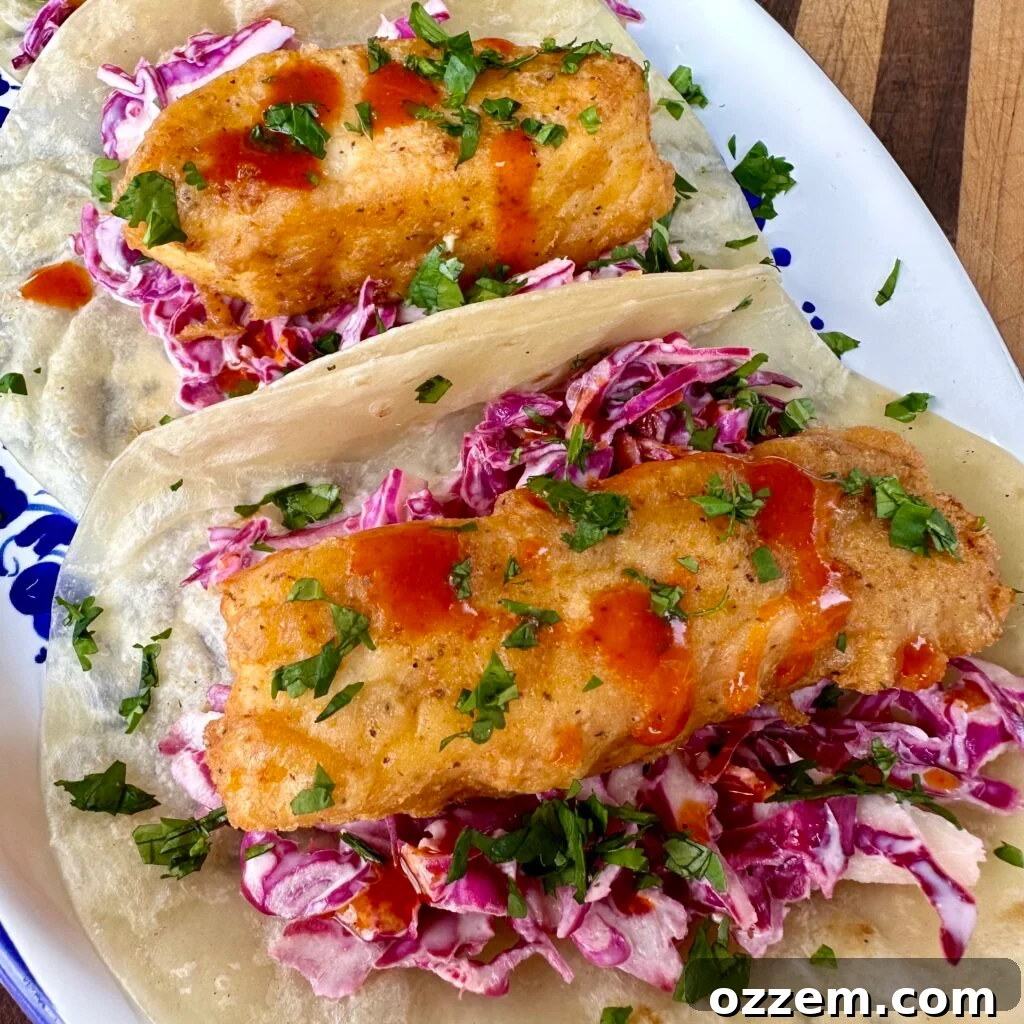 Plated crispy fish tacos with creamy coleslaw and lime