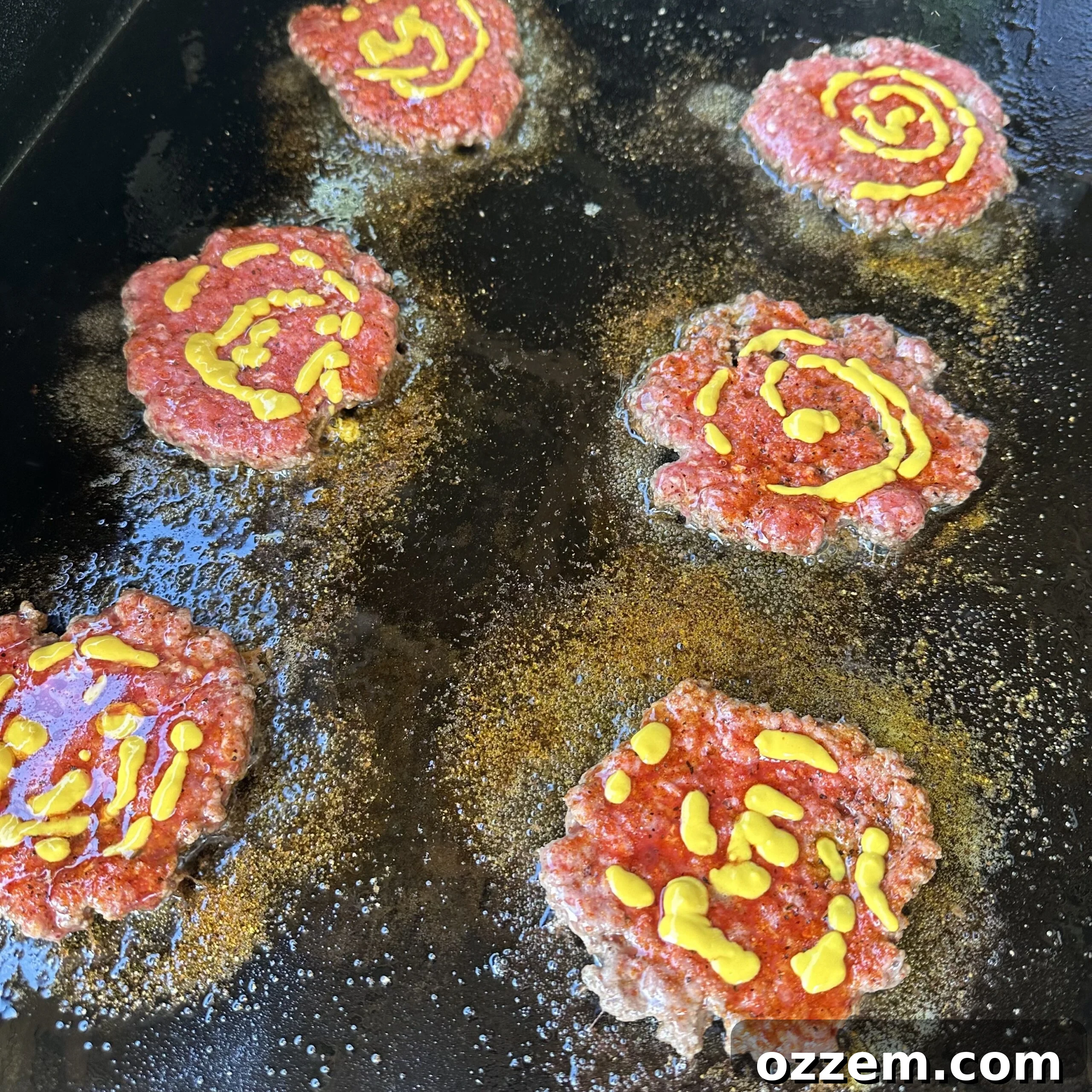 Burger patties with melting American cheese on a griddle