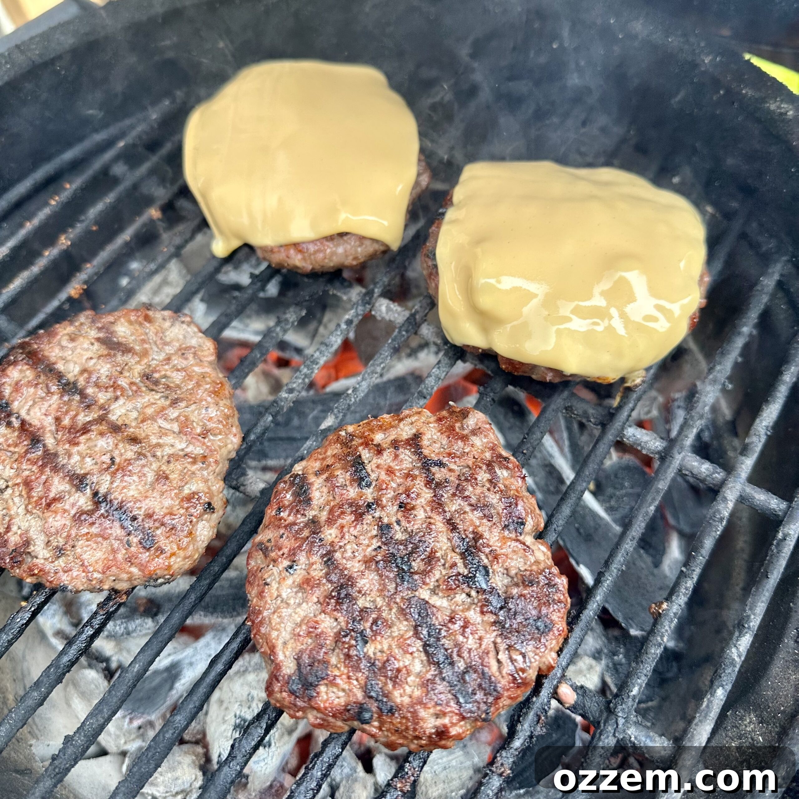 Grilled beef patties with melting American cheese, fresh off the grill.