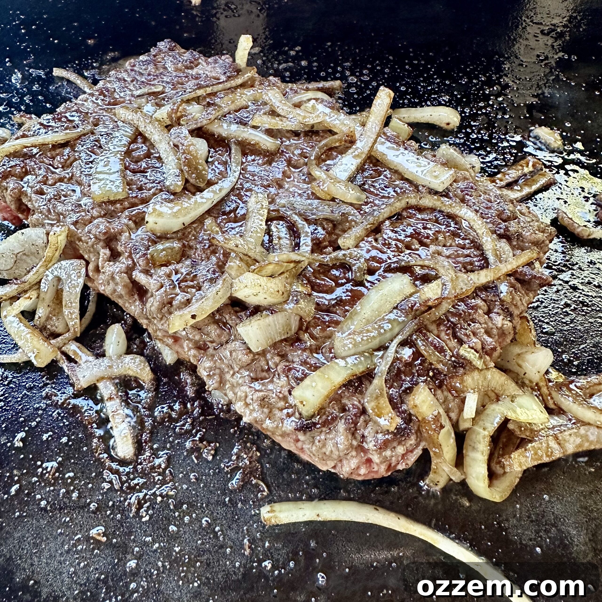 Ground beef and onions cooking on a griddle