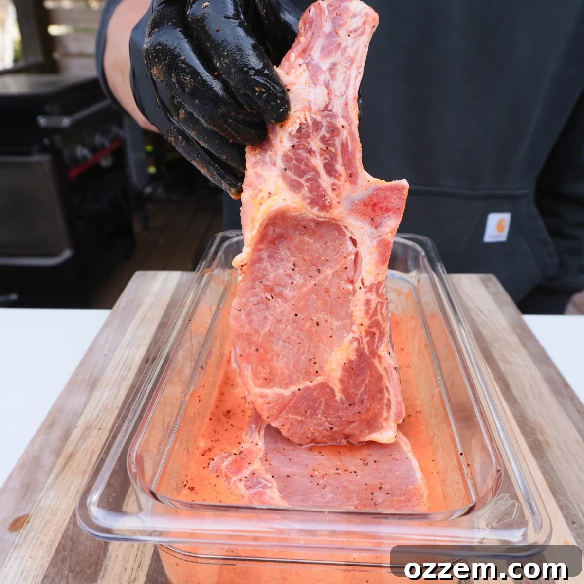 Succulent Pork Chops with Robust Beer Gravy 4 Pork chops soaking in a beer marinade with seasoning, ready for grilling.