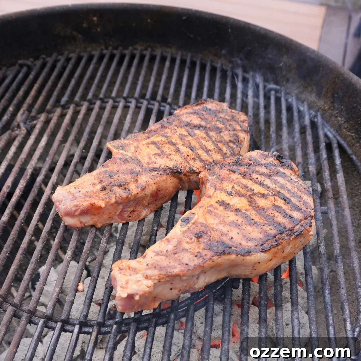Succulent Pork Chops with Robust Beer Gravy 7 Two bone-in pork chops sizzling on hot grill grates, showing a perfect sear.