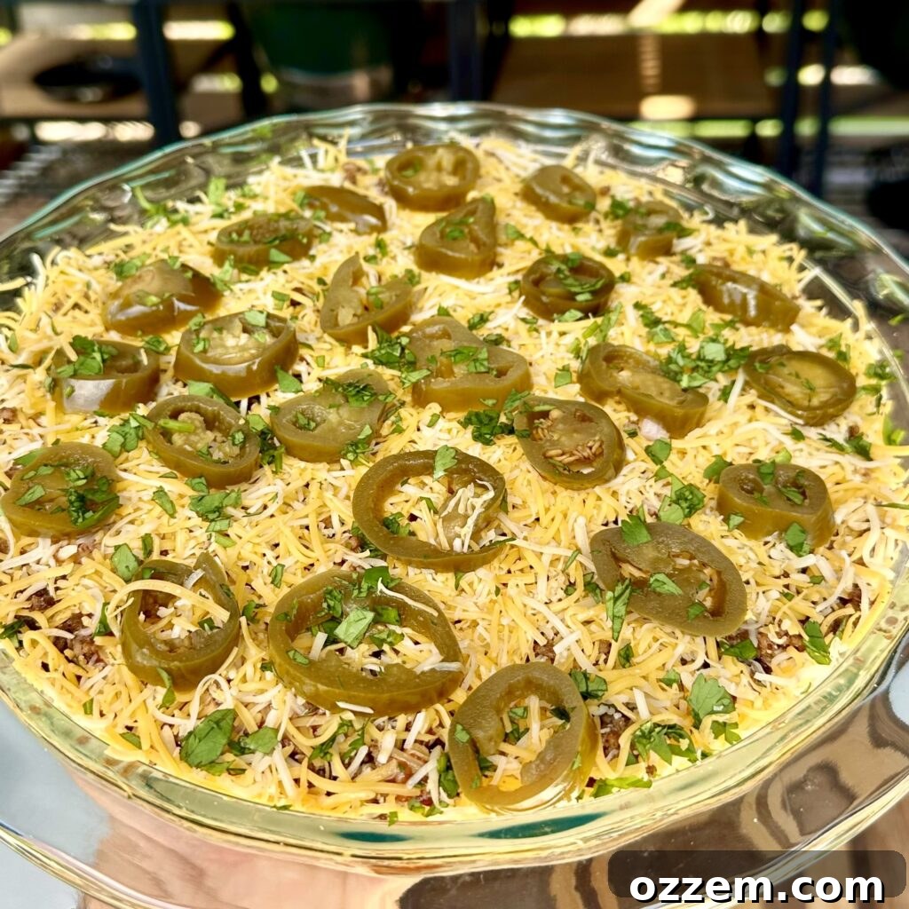 A vibrant eight-layer taco dip presented beautifully in a clear glass container, ready for serving.