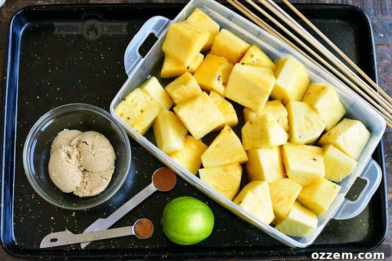 cut chunks of pineapple in a plastic container with lime, brown sugar, cinnamon, and cayenne pepper next to it in a black metal tray