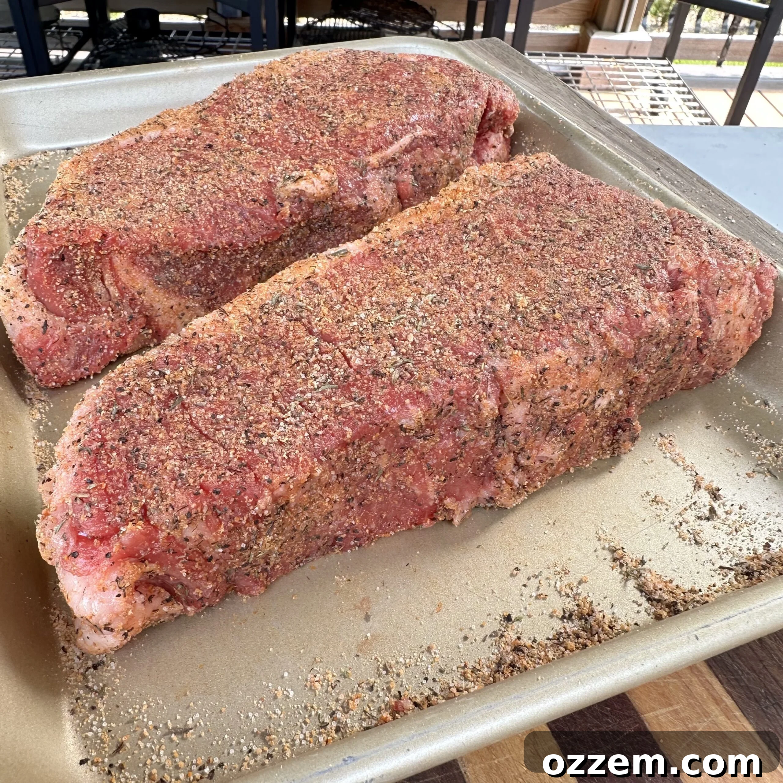 Generously seasoned New York Strip Steak, ready for grilling.