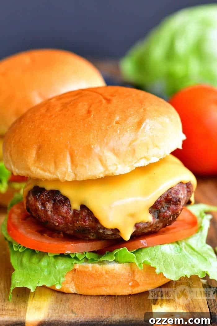 Close-up of a gourmet cheeseburger on a wooden board with fresh lettuce and tomato, showcasing a perfectly cooked patty.
