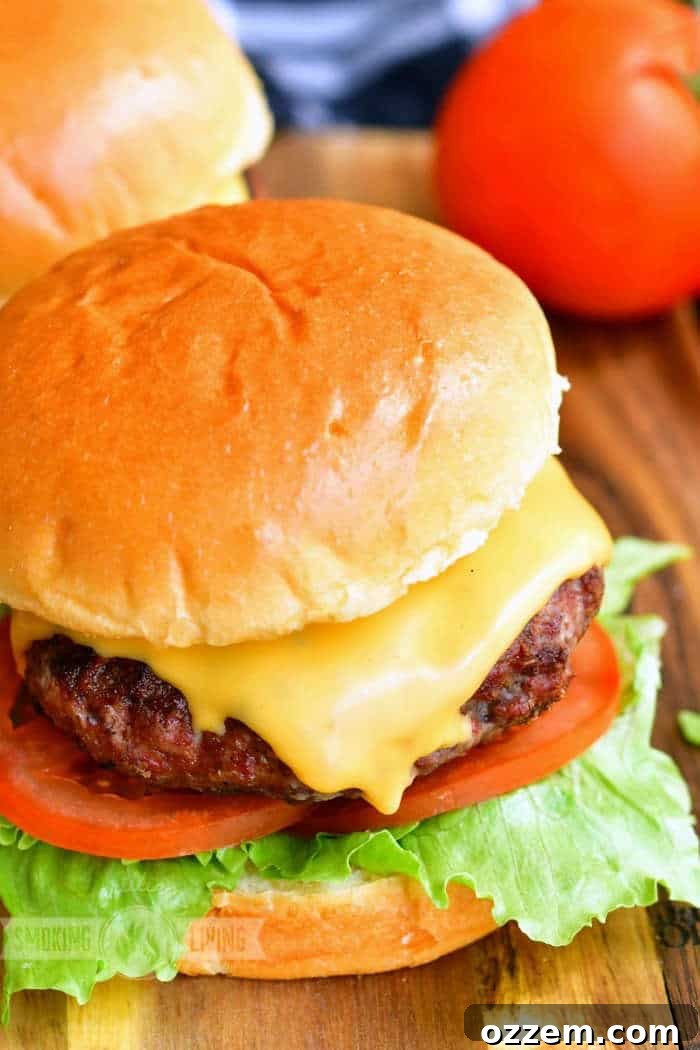 A perfectly assembled cheeseburger with fresh lettuce and tomato, served on a wooden board, highlighting its appealing presentation.